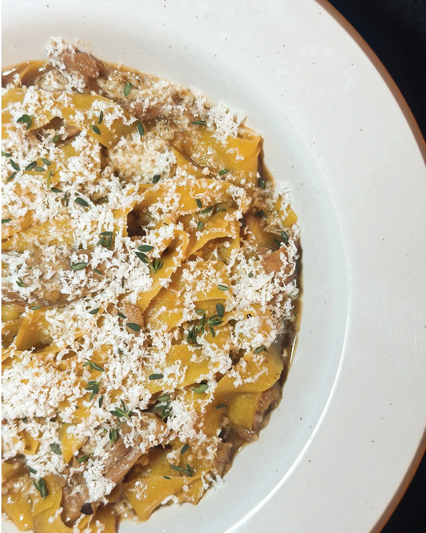 Pappardelle in ragù under a blanket of shaved cheese and thyme